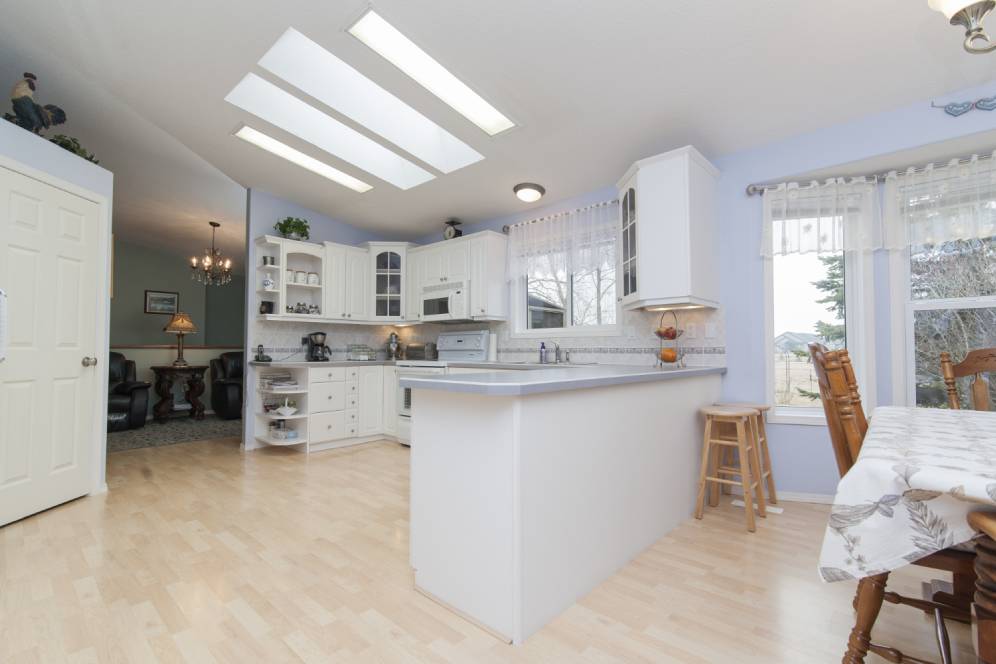 Bright kitchen with white cabinetry, skylights, and a dining area by the window.