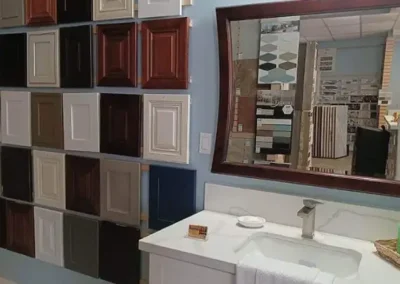 Bathroom with sample cabinet doors on wall and a large mirror reflecting the interior of a tile showroom